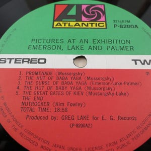 Puede incluir: Un disco de vinilo vintage con una etiqueta verde y roja que presenta el &aacute;lbum "Pictures at an Exhibition" de Emerson, Lake and Palmer. La etiqueta incluye los t&iacute;tulos de las pistas y el logotipo de Atlantic Records.