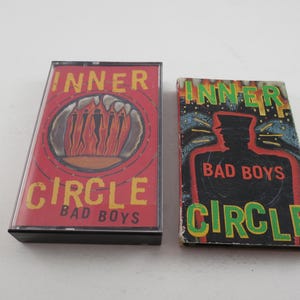 May include: Two cassette tapes with the same band, Inner Circle, but different album covers. The first tape has a red cover with a circle design and the text "Inner Circle Bad Boys". The second tape has a black and green cover with the text "Inner Circle Bad Boys" and a silhouette of a person.