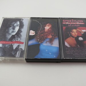 May include: Three cassette tapes with images of Gloria Estefan. The first tape is titled "Gloria Estefan  Cuts Both Ways". The second tape is titled "Gloria Estefan  Let It Loose". The third tape is titled "Gloria Estefan and Miami Sound Machine  Let It Loose".