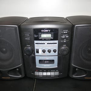 May include: Black Sony stereo boombox with two speakers and a central unit. The unit has a CD player, cassette player, and radio. The speakers are labeled "Mega Bass". The display shows "01:03:06".