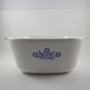 May include: White ceramic bowl with a blue floral design. The bowl has a rectangular shape with rounded corners and small handles on each side. The blue floral pattern is centered on the front of the bowl.