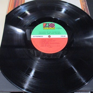 Op de afbeelding: Zwarte vinylplaat met een groen en rood label. Het label zegt "Pictures at an Exhibition, Emerson, Lake and Palmer" en "Stereo, E&eacute;n".