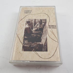 May include: Vintage cassette tape with the album title "The Songs of the Eagles" and the band name "Common Thread" printed on the cover. The cover features a sepia-toned image of two people. The cassette is encased in a clear plastic case.