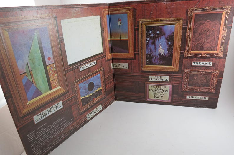 Puede incluir: Un libro abierto con obras de arte enmarcadas en una pared con paneles de madera. El arte incluye pinturas abstractas y paisajes, con t&iacute;tulos como "The Great Gates of Kiev" y "The Old Castle". El libro est&aacute; abierto, mostrando varias im&aacute;genes enmarcadas.
