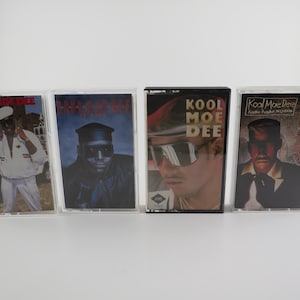 May include: Four cassette tapes with black and white images of men on the covers. The tapes are labeled "Kool Moe Dee", "How Ya Like Me Now", "Kool Moe Dee", and "Kool Moe Dee - How Ya Like Me Now".