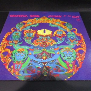 May include: A psychedelic album cover featuring a circular design with multiple faces and intricate patterns in shades of blue, green, yellow, orange, and red on a purple background. The text "GRATEFUL DEAD" and "AWAKE" is visible at the top of the cover.