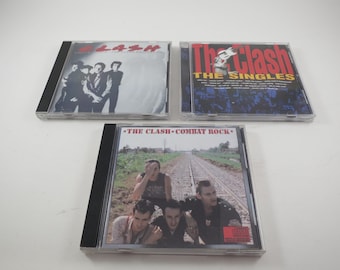May include: Three compact discs featuring The Clash. The first disc is titled "The Clash" and features a black and white photo of the band members. The second disc is titled "The Clash - The Singles" and features a photo of the band members in color. The third disc is titled "The Clash - Combat Rock" and features a photo of the band members in color.