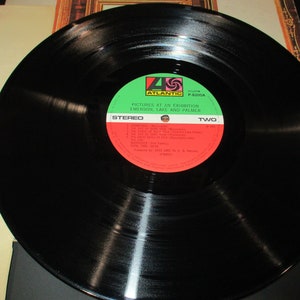Op de afbeelding: Zwarte vinylplaat met een groen en rood label. Het label zegt "Pictures at an Exhibition, Emerson, Lake and Palmer, Stereo, Two".