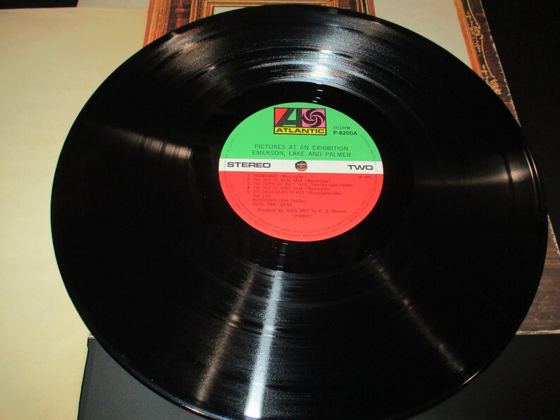 Op de afbeelding: Zwarte vinylplaat met een groen en rood label. Het label zegt "Pictures at an Exhibition, Emerson, Lake and Palmer, Stereo, Two".