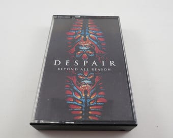 May include: A black cassette tape with a red, blue, and black graphic design. The text "DESPAIR BEYOND ALL REASON" is printed on the front of the tape.