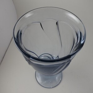 Pu&ograve; includere: Un calice di vetro trasparente tinto di blu, con un bordo ampio e decorativo e una base arrotondata. Il calice ha un design unico con linee curve e uno stelo. Il vetro &egrave; liscio e sembra essere fatto di un materiale resistente.