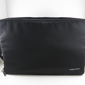 May include: Black rectangular Case Logic shoulder bag with a zipper closure and a black shoulder strap. The bag has a small green and white Case Logic logo on the lower right corner.