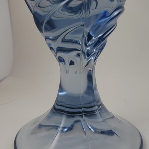 Pu&ograve; includere: Un vaso decorativo in vetro blu con un design a spirale e strutturato. Il vaso ha una base ampia che si assottiglia verso un collo stretto, per poi allargarsi di nuovo nella parte superiore. Il vetro ha una finitura lucida ed &egrave; traslucido.