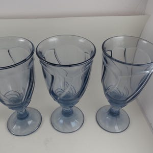 Pu&ograve; includere: Un set di quattro calici in vetro blu-tinto con un design decorativo a spirale. I calici hanno una forma a coppa arrotondata e poggiano su una base circolare. Le vetrerie sono adatte per servire bevande.