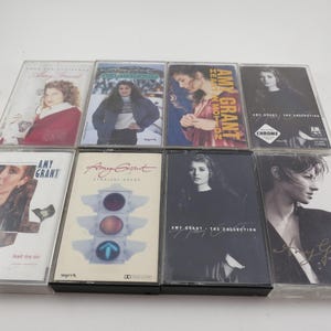 May include: A collection of eight vintage cassette tapes featuring Amy Grant albums. The album covers display images of Amy Grant, with titles such as "Lead Me On" and "Straight Ahead." The tapes are in clear plastic cases.