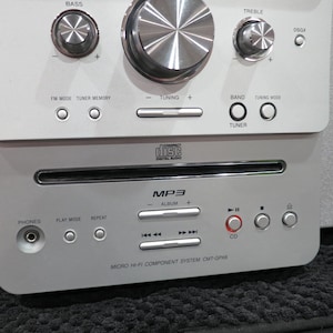 May include: Silver micro hi-fi component system with a CD player and MP3 capabilities. Features include bass, treble, and tuning controls. The system has a CD player and a headphone jack. The brand name "SONY" is visible on the side.