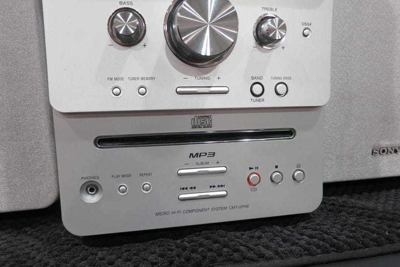 May include: Silver micro hi-fi component system with a CD player and MP3 capabilities. Features include bass, treble, and tuning controls. The system has a CD player and a headphone jack. The brand name "SONY" is visible on the side.