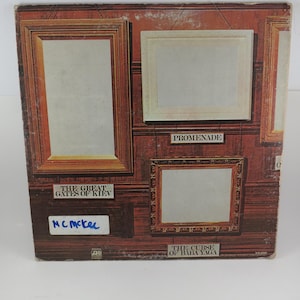 Puede incluir: Portada de &aacute;lbum con obras de arte enmarcadas sobre un fondo de madera oscura. El texto incluye "The Great Gates of Kiev", "Promenade" y "The Curse of Baba Yaga". El nombre "MC McKel" est&aacute; escrito con un rotulador azul.