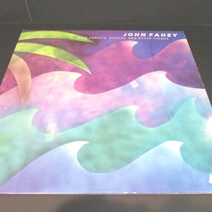 May include: A vinyl record album cover with a colorful abstract design of swirling waves in shades of green, purple, and blue. The album title is "Rain Forests, Oceans, and Other Themes" by John Fahey.