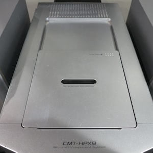 以下が含まれることがあります： CD SYNCHRO RECORDINGと記されたトップローディング式ディスクコンパートメントを備えた中央ユニットと、オーディオコンソールの両側に配置された2つのシルバーのスピーカーで構成される、シルバーのSony CMT-HPX9マイクロHi-Fiコンポーネントシステム。