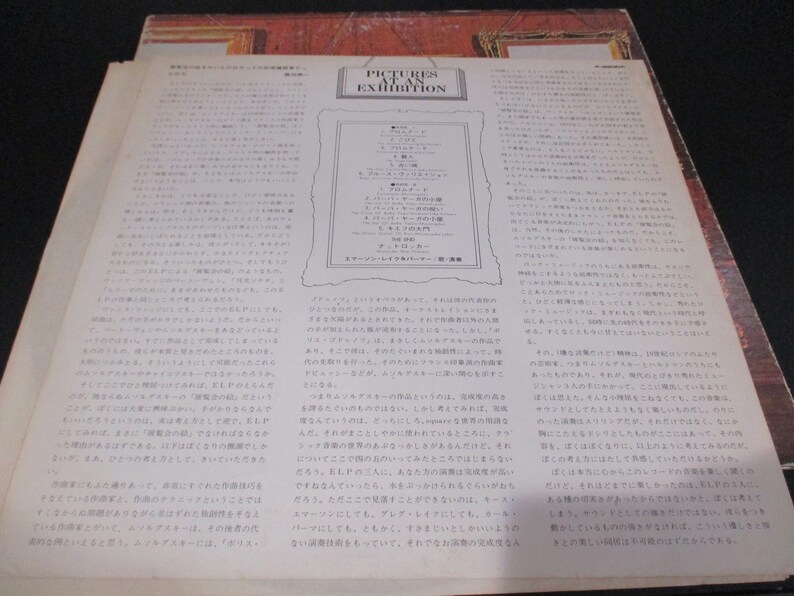 Op de afbeelding: Een vintage vinyl platenhoes met een zwart-wit afbeelding van een man in pak en stropdas. De albumtitel is "Pictures at an Exhibition" en de artiest is "Emerson, Lake & Palmer".