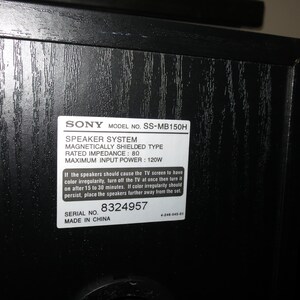 May include: A close-up of a black speaker cabinet with a white label. The label reads "SONY MODEL NO. SS-MB150H SPEAKER SYSTEM." The speaker is magnetically shielded with a rated impedance of 80 and a maximum input power of 120W. Serial number 8324957.
