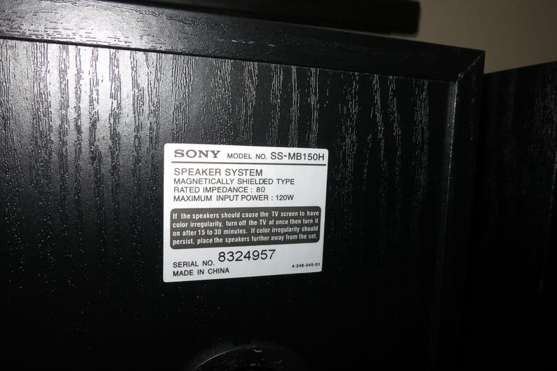 May include: A close-up of a black speaker cabinet with a white label. The label reads "SONY MODEL NO. SS-MB150H SPEAKER SYSTEM." The speaker is magnetically shielded with a rated impedance of 80 and a maximum input power of 120W. Serial number 8324957.