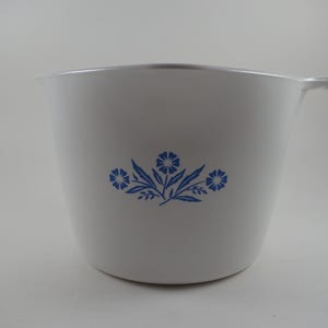 May include: White mixing bowl with a blue floral design. The bowl has a handle and a pouring spout. The floral design features three blue flowers with leaves. The bowl is made of a durable material.