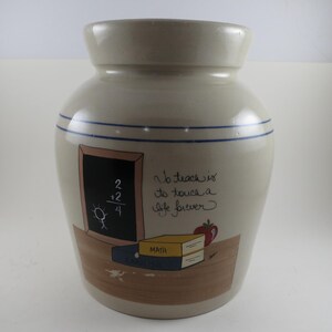 May include: A beige ceramic jar with a narrow neck and two blue stripes. The jar features a chalkboard with a math problem, a small stick figure, and the text "No trace is to touch a life forever."