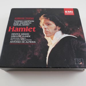 May include: A vintage EMI Classics CD box set of Ambrose Thomas's Hamlet opera. The cover features a portrait of a man in a dark coat and white collar. The title "Hamlet" is in red, with the names of the performers and orchestra.