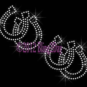 May include: A design of three interlocking circles made of white rhinestones on a black background. The design is surrounded by sparkling stars.