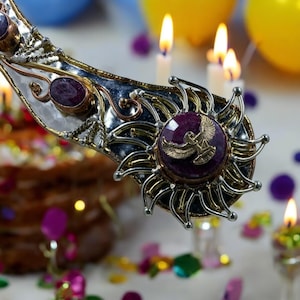 May include: A silver and gold pendant with a purple gemstone and a gold eagle design. The pendant is surrounded by a decorative silver and gold frame.