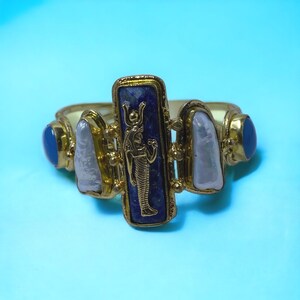 This Ancient Egyptian Isis charm features a Lapis Lazuli stone on a cuff bracelet embellished with 2 white pearls and 2 blue agate stones. image 9