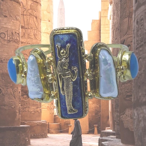 This Ancient Egyptian Isis charm features a Lapis Lazuli stone on a cuff bracelet embellished with 2 white pearls and 2 blue agate stones.