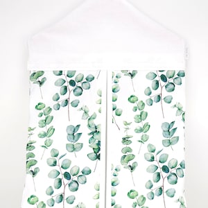 May include: White hanging organizer with a eucalyptus leaf pattern. The organizer has two compartments and a white hanger.