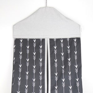 May include: A gray and black hanging diaper caddy with a white arrow pattern. The caddy has a gray top and a black bottom with white arrows.