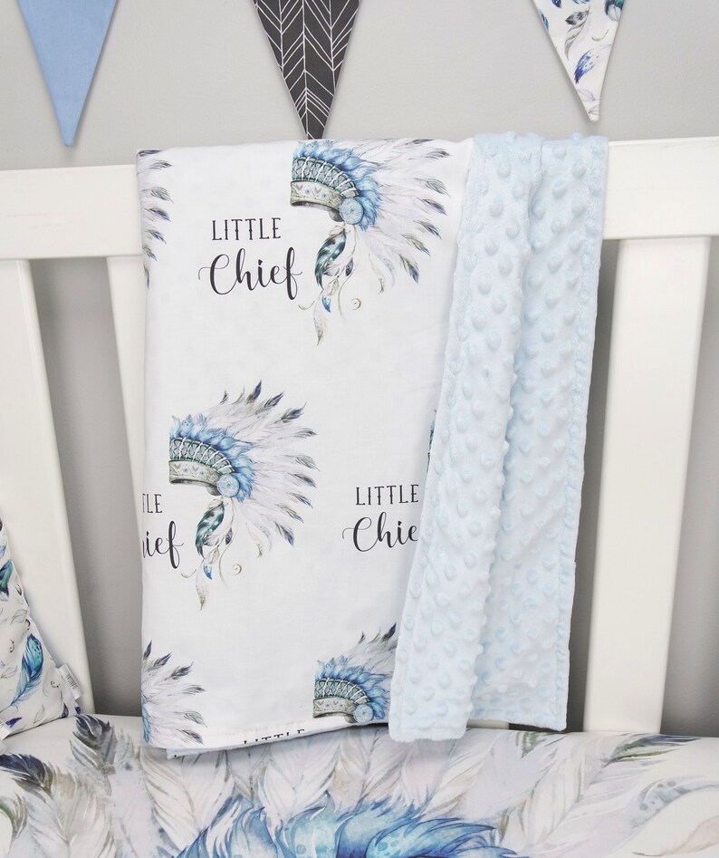 Puede incluir: Una manta de beb&eacute; blanca con un patr&oacute;n de tocado azul y blanco y el texto "Little Chief" repetido. La manta se combina con una manta de minky azul claro.