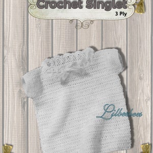May include: A white crocheted singlet with short sleeves, made with 3 ply yarn. The singlet is laid flat on a woodgrain background.