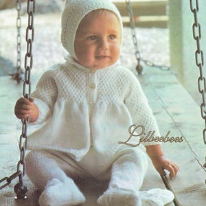 May include: A white knitted baby outfit set including a jacket, leggings, pixie hood, and mittens. The set is made with double knit yarn and is designed to fit a newborn to 2 years old.
