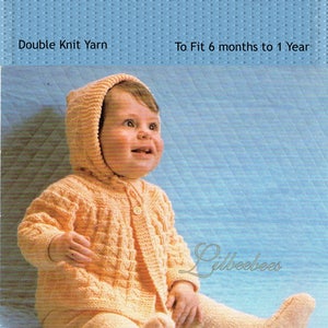 May include: A knitted hooded coat and leggings set in a peach color for a baby. The set is made with double knit yarn and is designed to fit a baby from 6 months to 1 year old. The image shows a baby wearing the set, sitting on a blue background.
