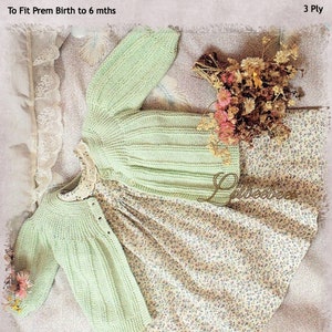May include: A light green knitted baby jacket with a button closure. The jacket is laid out on a floral fabric with a bouquet of dried flowers. The text "Baby Jacket" is written in a circle at the top of the image. The text "To Fit Prem Birth to 6 mths" is written below the circle. The text "3 Ply" is written in the top right corner of the image.
