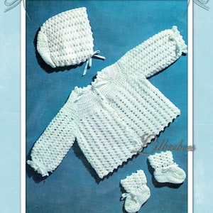 Può includere: Un set per carrozzina all'uncinetto bianco, composto da cappellino, cardigan e scarpine, presentato su sfondo blu. Il set presenta un motivo a punto strutturato e delicati dettagli in nastro. Il testo "CROCHETED PRAM SET IN 3 PLY" è in alto.