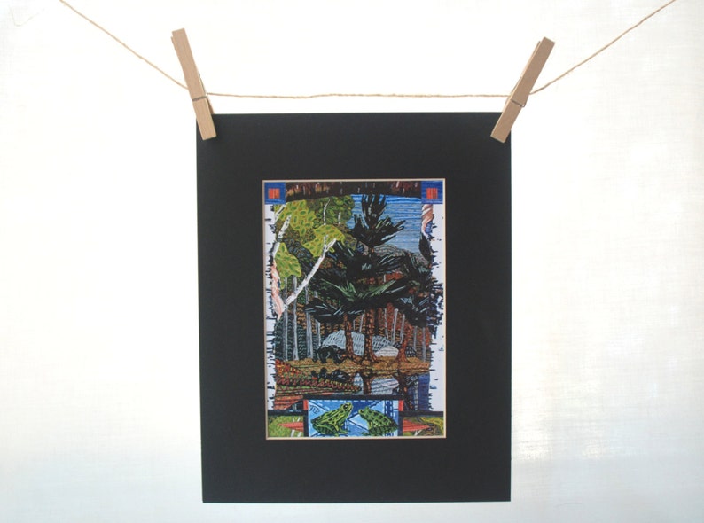 May include: A framed print of a colourful, abstract landscape with trees, water, and a blue sky. The print is surrounded by a black mount and a white frame.