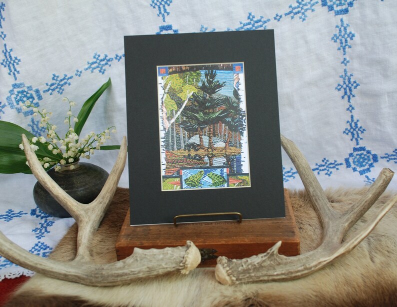 May include: A framed print of a colourful, abstract landscape with trees and geometric shapes. The print is matted in black and has a wooden frame.