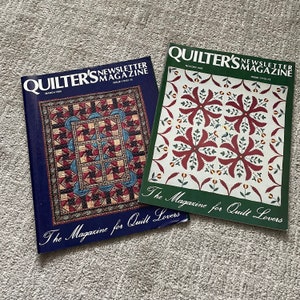 Puede incluir: Dos números de la revista Quilter's Newsletter Magazine. El número de marzo de 1988 presenta una colcha con un patrón azul y rojo. El número de noviembre/diciembre de 1988 presenta una colcha con un patrón rojo y blanco. Ambas revistas tienen el texto "The Magazine for Quilt Lovers" en la portada.