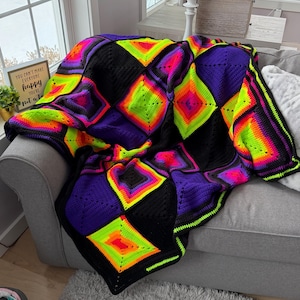 May include: A vibrant, handmade crochet blanket with a geometric diamond pattern. The blanket features neon green, pink, orange, purple, and black squares. The blanket is draped over a gray sofa.