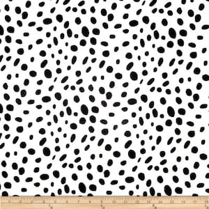 Puede incluir: Tela blanca con un patrón de manchas negras de dálmata. Las manchas son irregulares en tamaño y forma.