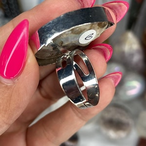 May include: A silver ring with a large, irregular shaped, white and grey agate stone. The ring is adjustable and has a silver band.
