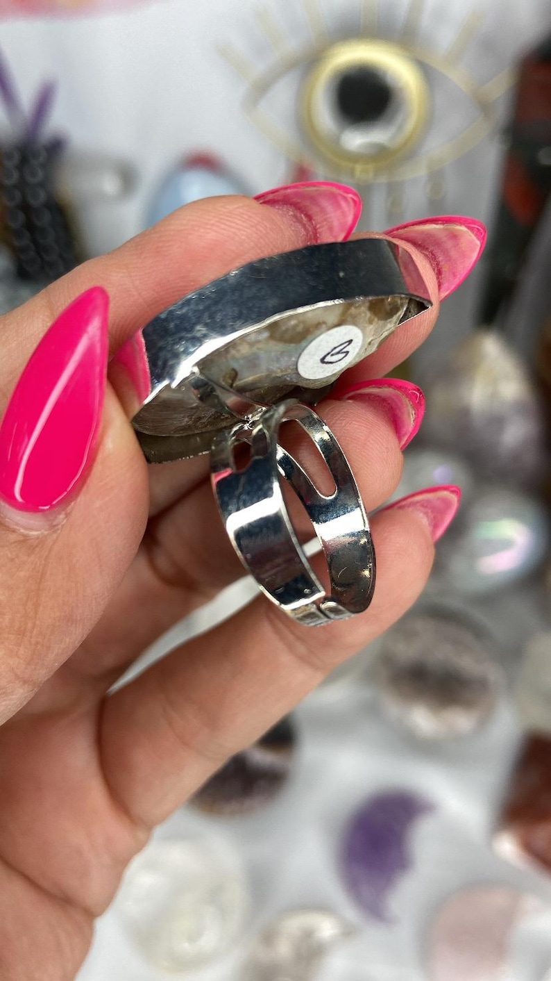 May include: A silver ring with a large, irregular shaped, white and grey agate stone. The ring is adjustable and has a silver band.