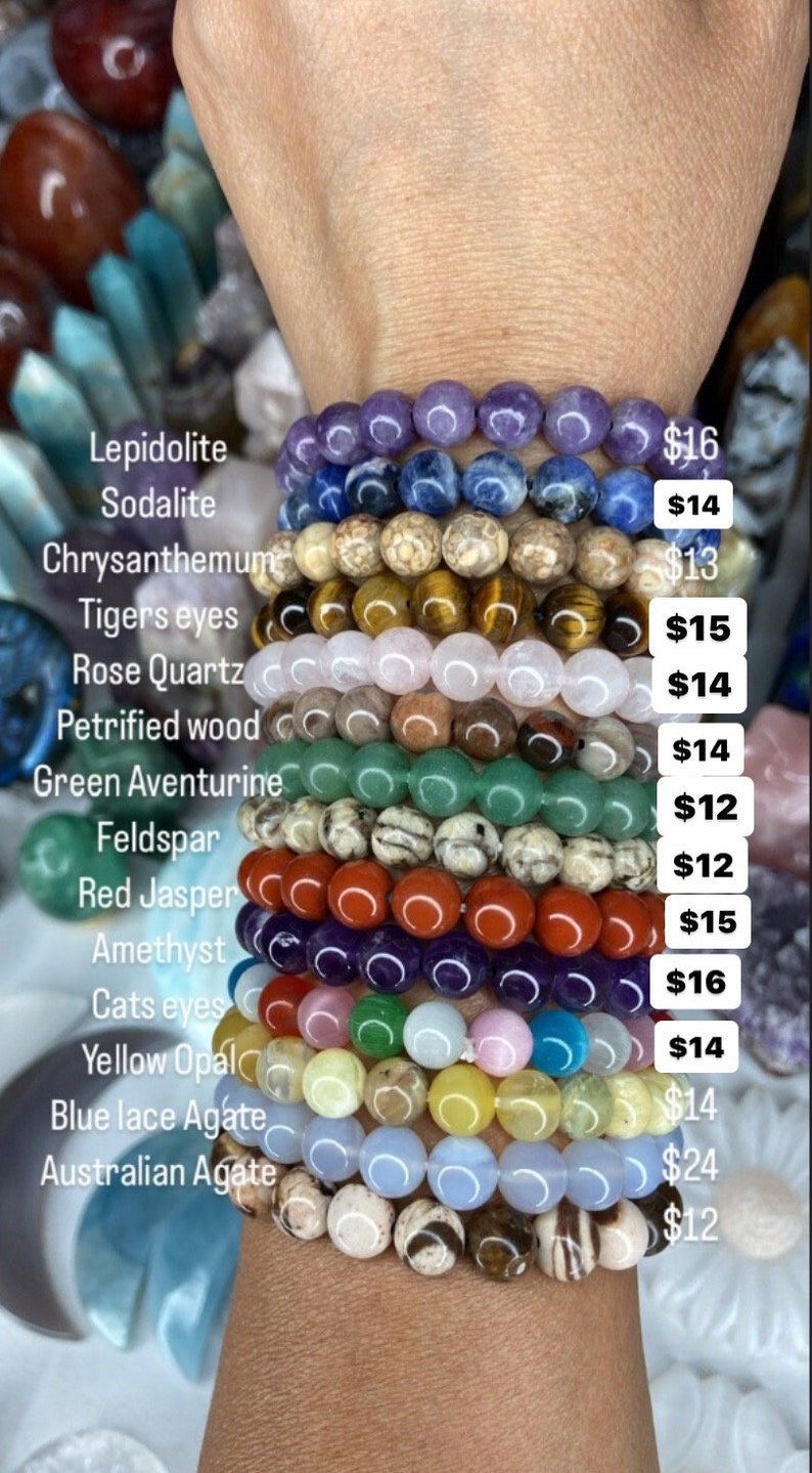 K&ouml;nnte beinhalten: Ein Stapel von 12 Armb&auml;ndern aus verschiedenen Edelsteinen, darunter Amethyst, Rosenquarz, Tigerauge und gr&uuml;ner Aventurin. Jedes Armband ist mit der Art des Steins und dem Preis gekennzeichnet.
